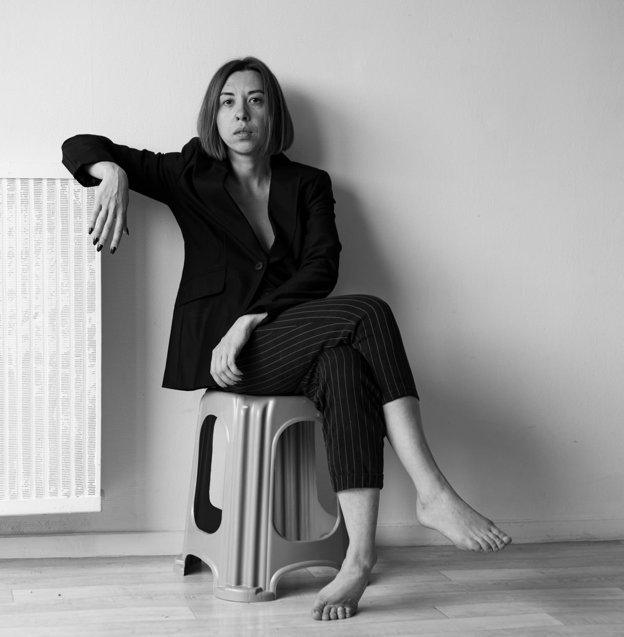 Black-and-white portrait of Oleksandra Dementieva, seated in a black suit and looking into the camera